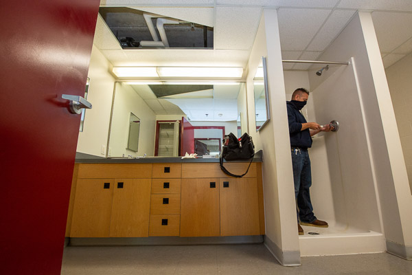 Michael R. Smith, HVAC/plumbing and general maintenance mechanic for residence halls, performs a plumbing repair in a Lancaster Hall bathroom. 