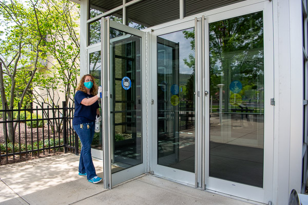 Mindy J. Colony, a first-shift custodian, disinfects entry doors at the SASC.