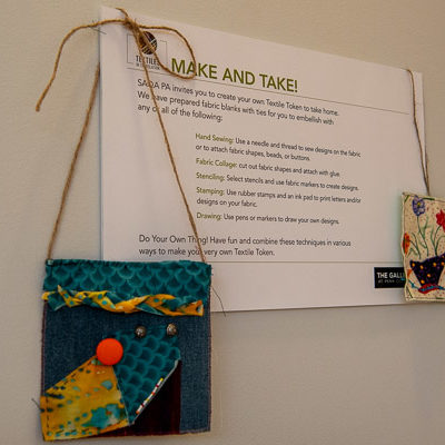 In the gallery lobby, visitors are invited to create a “textile token” using fabric pieces and an array of artistic embellishments.
