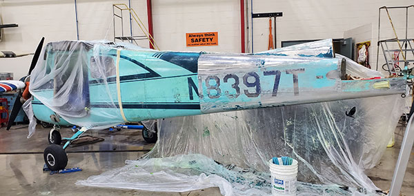 Some surfaces required multiple applications of chemical stripper. Following removal of the wings and tail section, this is how the fuselage looked – half original paint, half nearly down to bare metal.