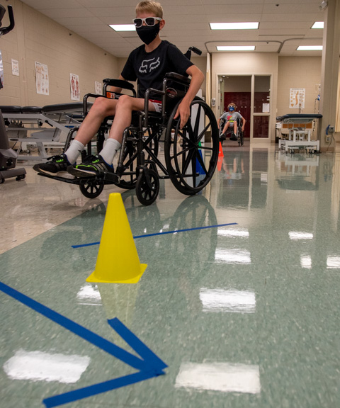 A youngster rolls through an obstacle course in the physical therapist assistant lab, gaining sensitivity to the difficulties in maneuvering a wheelchair.