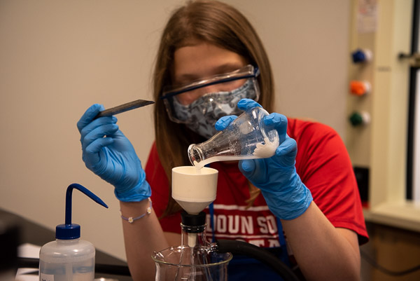 Focused on the task at hand, a camper makes aspirin in a chemistry lab.