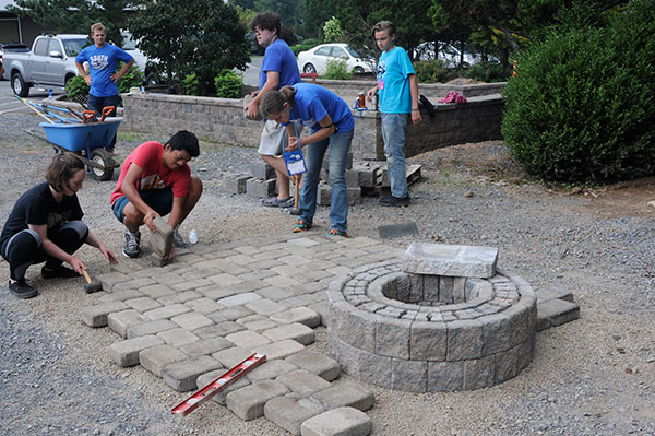 Teens in Design, Build & Grow Landscape & Horticulture install pavers around the temporary fire pit that they installed at the Schneebeli Earth Science Center.