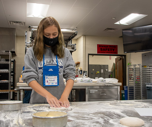 Stretching dough for a personal pizza in the baking lab