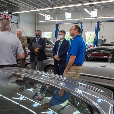 Reasner (left foreground) and Van Stavoren (right) talk with the day's guests in an automotive lab. From left are Tomlinson, Fiore, Hess and Topper.
