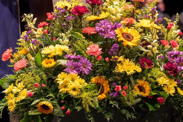 A beautiful arrangement at the base of the podium brings a touch of summer – so obvious in the sun-dried air beyond the theater doors – to the proceedings inside.
