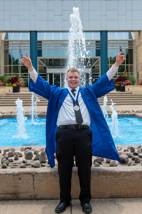 With his robe refreshingly unfastened and the Veterans Fountain spouting cool water, surgical technology alumnus Timothy E. Singer, of Rimersburg, raises his arms in accomplishment. Around his neck is a medal marking his service as a Resident Assistant, helping first-year students transition from back-home accommodations to on-campus housing.
