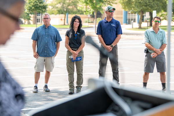 Physics professor David S. Richards (left), one of Cooley's supportive faculty colleagues, listens to presidential remarks alongside behind-the-scenes creators Dildine, Karstetter and Draus. 