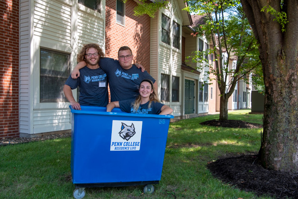 Welcoming residents to The Village are RAs Zachary M. Beekley (left), Christopher J. Bajek and Rebecca E. High (in bin). 