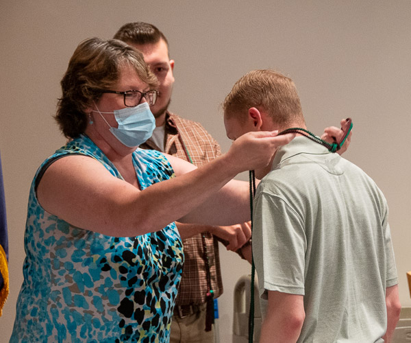 Karen L. Plankenhorn, clinical supervisor for radiography, presents the cords for the Pennsylvania Sigma Tau Chapter of Lambda Nu to Dawson Coates, of Harrison Valley. Lambda Nu is a national honor society for the radiologic and imaging sciences. The chapter was established at Penn College in June 2020. In background is inductee Hunter W. Adams, of Mount Union. Eight 2021 graduates were inducted.