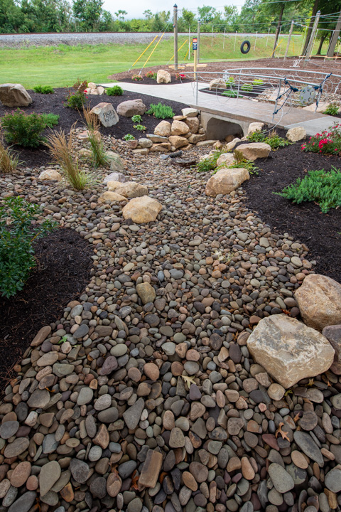Artfully placed stones blend with the natural surroundings between campus and the river.