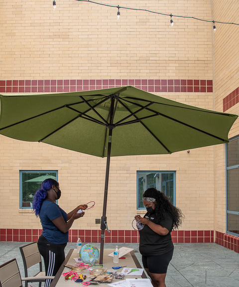 Under an umbrella, guests explore the craft of “dreamcatchers” …