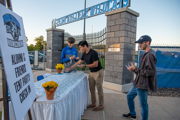 Checking in and grabbing a sampling glass are 2021 graphic design graduates Joey M. Morrin (center) and Tyler W. Miller. Assisting is Becky J. Shaner, senior manager of donor relations and special events.
