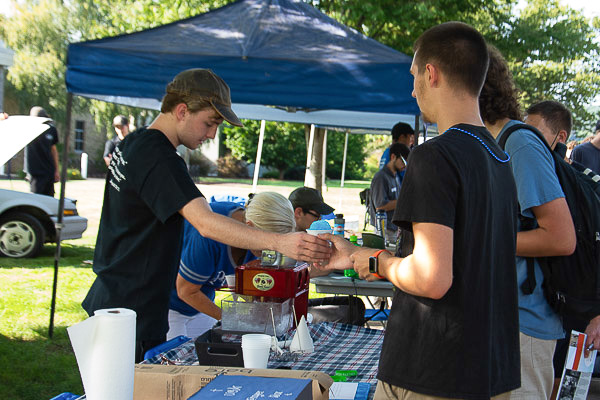 A United Campus Ministries member helps a visitor beat the heat with a blue raspberry snow cone.