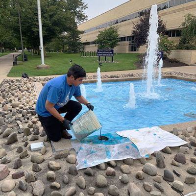 Marking the ninth year of a fall tradition, SGA President Robert A. Luna takes his turn adding the blue dye that will circulate through the fountain.