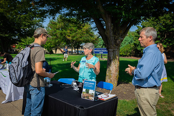 Recruiting facilitators for the Fish Challenge Course are Brenda A. Wiegand, manager of internal facilities and events; Rob Cooley, associate professor of anthropology and environmental science, who conceived of the course; and (in background) Deb B. Wescott, manager of conference and guest relations. (Photo by Frank T. Kocsis III, a graphic design student from Dickson City)