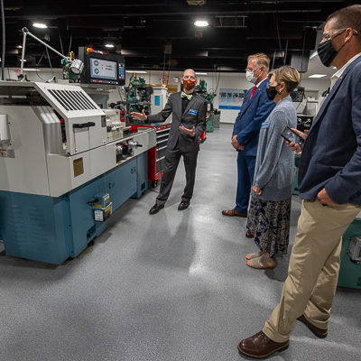 Kathleen D. Chesmel, assistant dean for materials science and engineering technologies, joins the legislators during a tour of the machining and manufacturing labs.