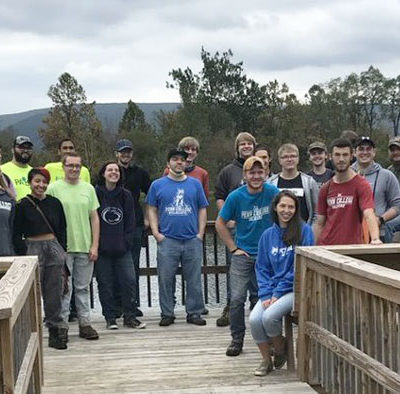 The group gathers on the student-constructed deck leading to the freshly reclaimed and beautified pond.