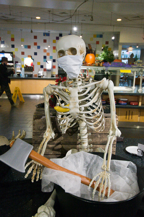 A skeletal staffer demonstrates proper masking while effectively curtailing food waste.