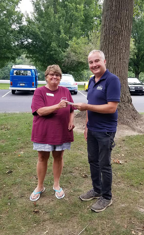 Deb Cyrus, president of the Harrisburg Area Volkswagen Owners Club, presents a $2,000 check to Roy H. Klinger, instructor of collision repair at Pennsylvania College of Technology, during a fall meet-up in Harrisburg’s Fort Hunter Park. The money will be added to the club’s scholarship fund, which assists students in the college’s automotive restoration certificate program. (Photo provided)
