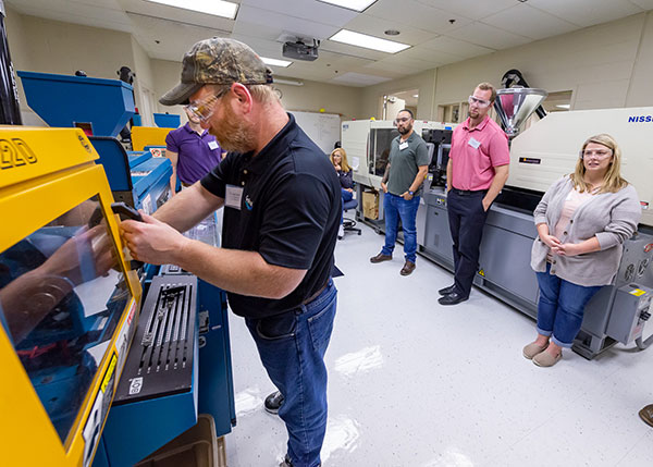 Thomas Horn (foreground), of Cardinal Systems Inc. in Schuylkill Haven, gets some hands-on exposure to Pennsylvania College of Technology's injection molding lab during a Summer 2021 Plastics Materials, Processing and Testing workshop on the college's main campus in Williamsport. (Editor’s note: The photo was taken before the college instituted an indoor masking protocol for everyone, regardless of vaccination status.)