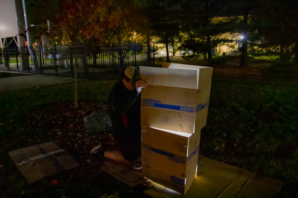 A student assembles boxes into a makeshift shelter ...