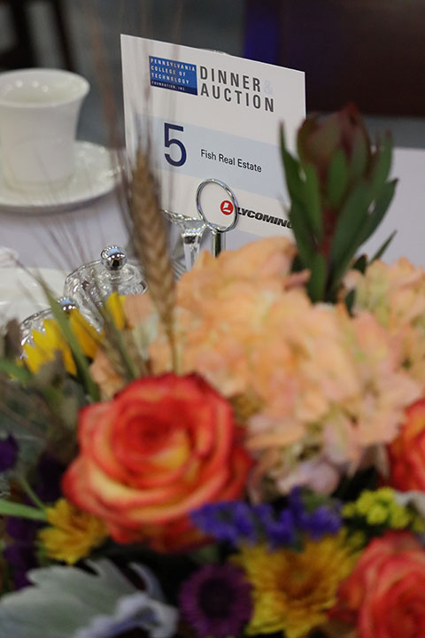 A seasonal arrangement frames a card denoting Fish Real Estate as that table's sponsor. The centerpieces were created by Karen R. Ruhl and her floral design students.