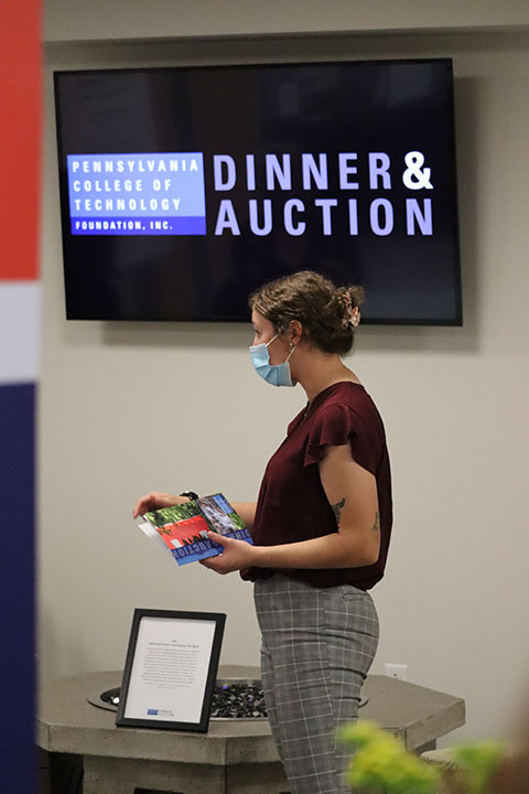 Surveying technology alumna Madison L. Kistler, of Kutztown, pursuing additional degrees in applied technology studies and concrete science technology, explains the ConCreate Design Club's fire ring contribution to the crowd.