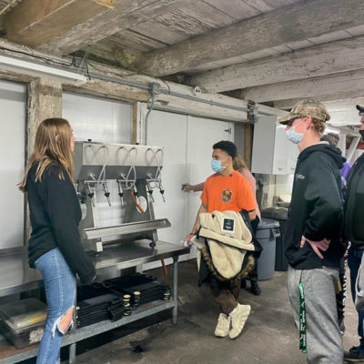 Winemaker Kayla Hosterman (left) shows the bottling system for small operations. The winery can produce 17 types of wines from various grape varietals, plus eight wines made from natural, non-grape fruit juice.
