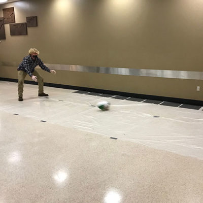 A two-handed delivery sends a frozen bird "flying" toward a bank of soda-bottle pins.