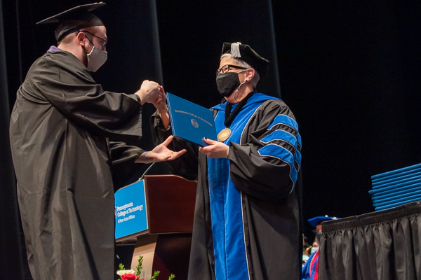Sanitizing between every encounter, the fully vaccinated Gilmour offered graduates their choice of greeting. (Applied management grad Mark J. Carter opted for a fist bump.)