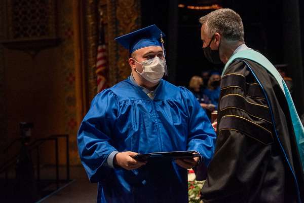 Nursing graduate Francis M. McMahon accepts a pair of honors – and congratulations from Michael J. Reed, vice president for academic affairs and provost. McMahon was presented with the Spirit of Nursing and the Nursing Peer Recognition awards.