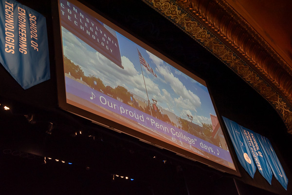 The lyrics to the college alma mater, against the breathtaking backdrop of campus aerial photos, are projected for the graduates and their supporters.