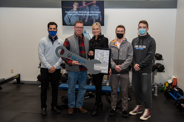 Coach Miller presented the Klingermans with a framed plaque of wrestlers’ signatures and the “Gritty Kitty of the Week” award, a wrench-shaped “trophy” honoring the week’s outstanding team member. Joining the festivities were senior wrestlers Colin J. Jens (in black mask) and Jesse J. Walker (far right). Jens, who wrestles at 141 pounds, is a business administration: marketing concentration student from Centreville, Md.; Walker, at 149 pounds, is from Ridgefield, Conn., and is enrolled in web and interactive media.