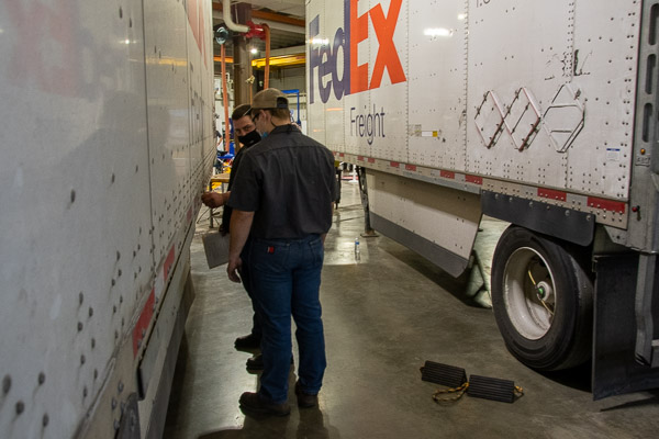 An industry representative mentors a student at the trailer preventive maintenance inspection station.