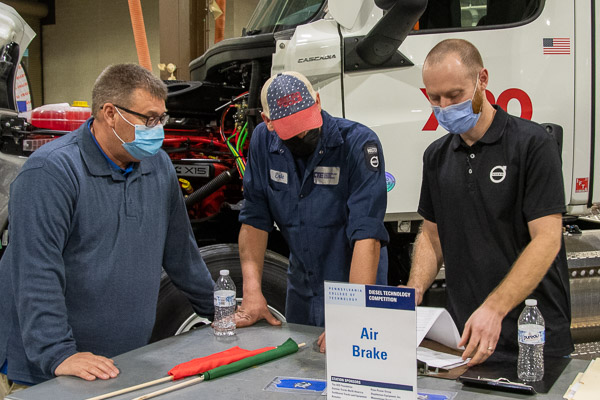 Cumberland Truck Equipment reps review score sheets at the air brake station. From left are Doug Stauffer and Penn College diesel technology grads Eric Sander (2019) and Derrick Bowersox (2010).