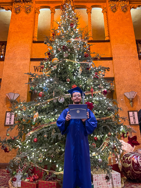 Finley M. Wright, landscape/horticulture technology: plant production emphasis, stands in front of the 20-foot CAC tree, grown on the farm of one of his instructors – Justin Shelinski. <br />(Photo by Megan L. Ripka, assistant director of marketing for academic programs and special projects)