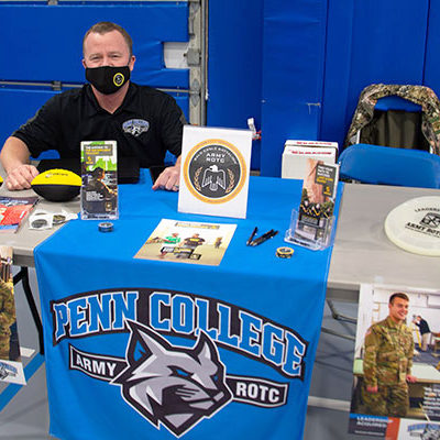 Among the ever-helpful college employees in attendance, Army ROTC instructor David E. Tice staffs a tableful of information for those interested in Bald Eagle Battalion service.
