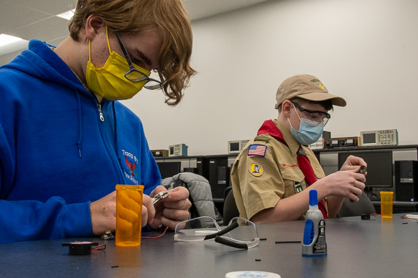 Scouts strip wires that, paired with a pill bottle, cotton balls, a 9-volt battery and a smoke detector buzzer, make a gadget.