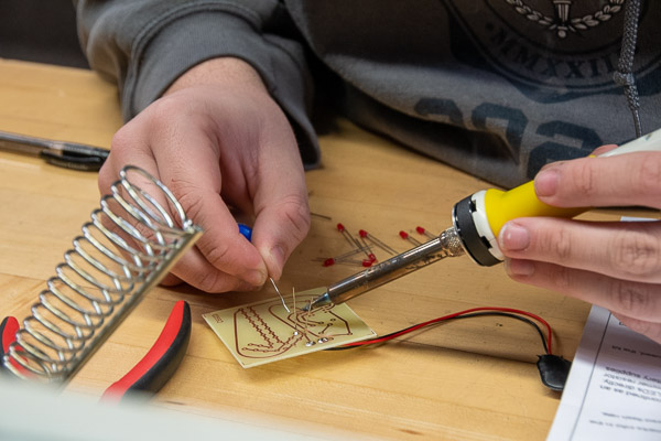 A Scout solders an LED light onto a circuit board.
