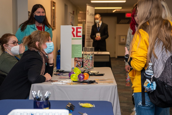 Career coach Kelly A. Gartner (at left in black top), who earned a Penn College degree in occupational therapy assistant last year, chats with young guests at a BLaST IU 17 table full of colorful giveaways.