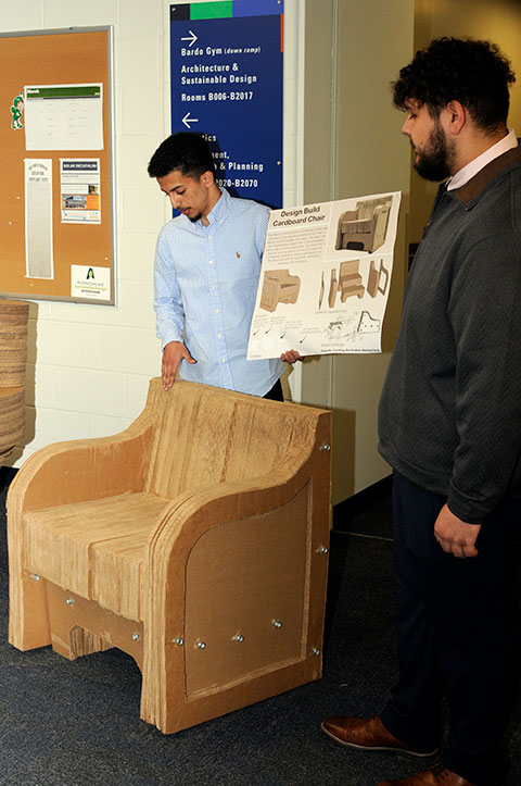 Beshoy A. Farid (left), of Lancaster, and Ben M. Kratzer, of Middleburg, share the particulars of their design, which includes eye-pleasing armrests and a combined seat and back for stability. (Not present was Cole S. King, of York Springs.)