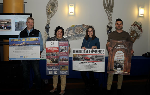 Faculty members hold display boards touting the Global Experiences trips that they will be leading. From left are Rob Cooley, associate professor of anthropology/environmental science (Alaska); Mary G. Trometter, assistant professor of hospitality management/culinary arts (Italy); Kathleen V. McNaul, LEAP adviser-international (representing Roy H. Klinger, collision repair instructor, traveling with students to Italy and France); and Naim N. Jabbour, assistant professor of architecture (Spain).