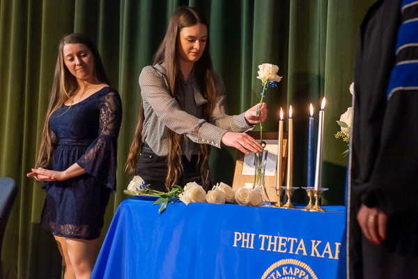 As Rowland and President Gilmour look on, Madison Gift places a rose in the vase in memory of Ashley Gentile-Wing. The residential construction technology and management student, who died March 6 from injuries sustained in a vehicle accident, was posthumously inducted.