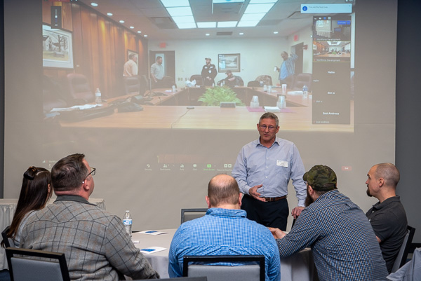 As the apprentices (on screen) finish their final class in a nearby conference room, Fry talks with West Pharmaceutical Services representatives.