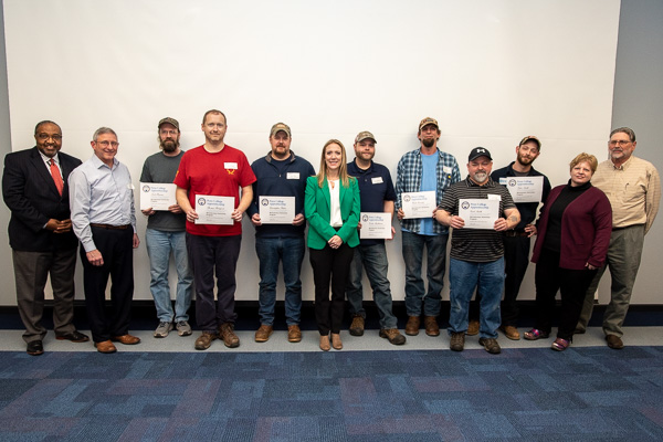 The group expands to include the apprentices' proud advocates. From left: Joseph Bass, apprenticeship and training representative for the state's Apprenticeship and Training Office; Fry; Barnes; Botsford; Fisher; Loew; Stackhouse; Greenly; Carl Smith; Tyler Smith; Christina Miller, ATO apprenticeship and training representative; and Kuhar.