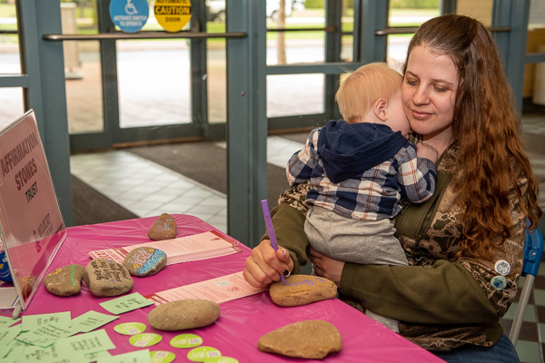 At the “Affirmation Stones” activity, Alicia A. Dobbs juggles creativity and motherhood. She is enrolled in human services & restorative justice. 