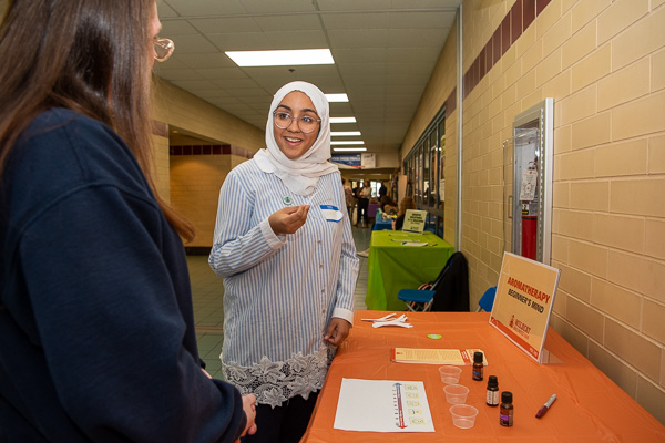 Taking a break from staffing another display, Samar Alquraish (right), a nursing student enrolled in PSY410, visits the aromatherapy table and chats with Serenity Hamlin, human services & restorative justice. 