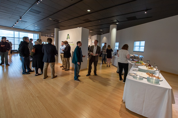 With the gallery lobby filled with work by two art faculty, food for the reception was moved into the main space. Rob A. Wozniak (in white shirt at right center), associate professor of architecture and planned August retiree, talks with a guest.
