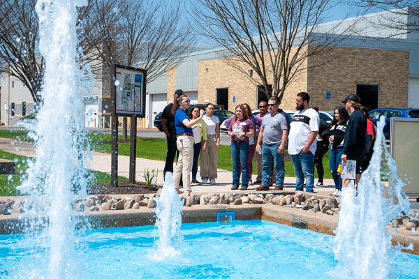 Student Ambassador Sophia B. Wiest leads a “Traditions Tour” along the campus mall. This stop features the Veterans Fountain, dyed blue every Homecoming and Parent & Family Weekend to show the campus's Wildcat pride.